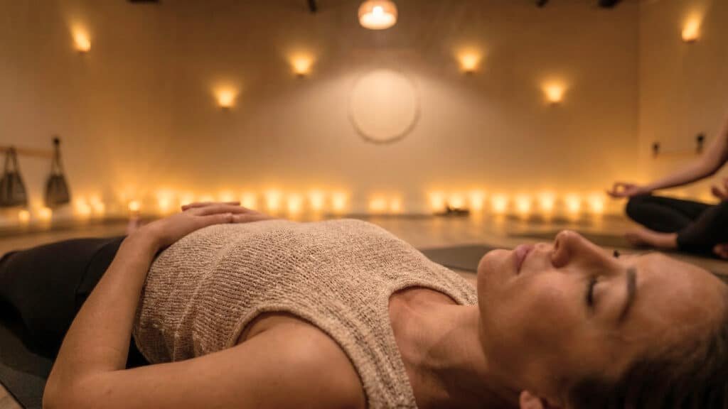 Student relaxing during restorative yoga in a candlelit Oakville studio